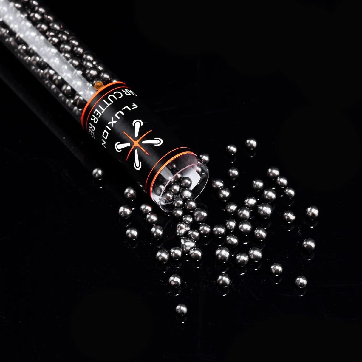 Flux Tar Cutter carbon bead refill tipped over on black surface with beads spilling in scattered pile