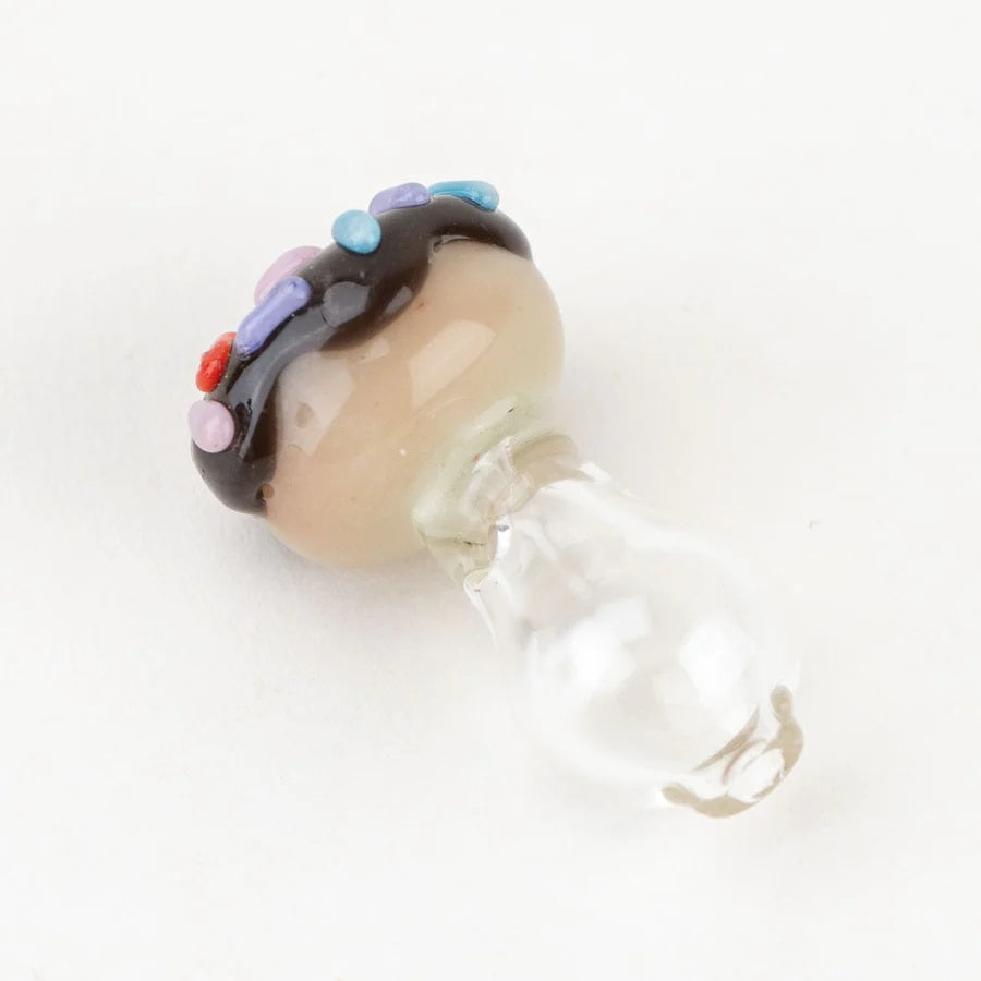 Side view of Empire Glassworks donut Peak Pro ball cap with glossy glaze and sprinkles atop a clear glass base, photographed on white.