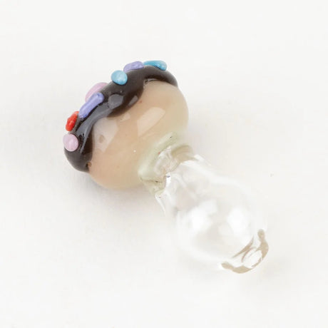 Side view of Empire Glassworks donut Peak Pro ball cap with glossy glaze and sprinkles atop a clear glass base, photographed on white.