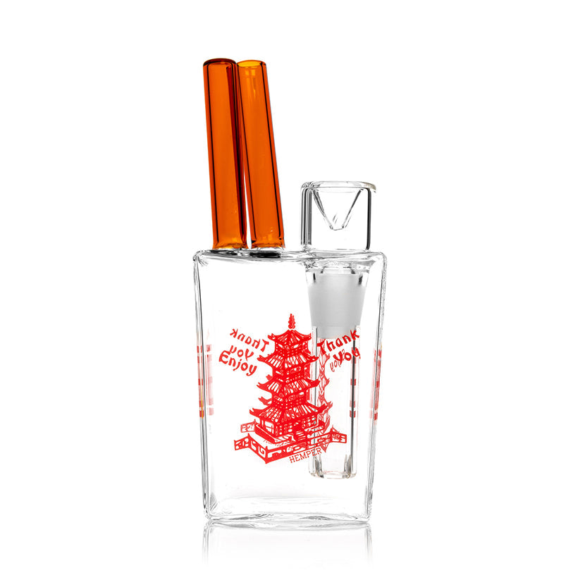 Hemper Chinese Takeout Box mini bong posed in front of matching packaging, clear 6-inch glass body with red artwork and upright chopsticks.