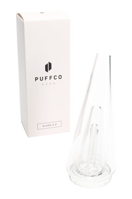 Clear Puffco Peak Glass 2.0 replacement top shown beside retail box, tapered cone body with internal downstem for water filtration.