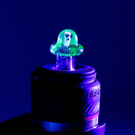 Martian ball cap installed on a Puffco Peak Pro under blacklight, neon green glow highlighting the alien figure.