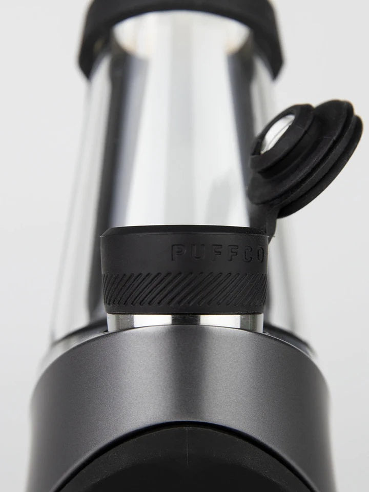 Macro view of Oculus-style cap and tether mounted to chamber, Puffco branding on textured silicone ring in Onyx.