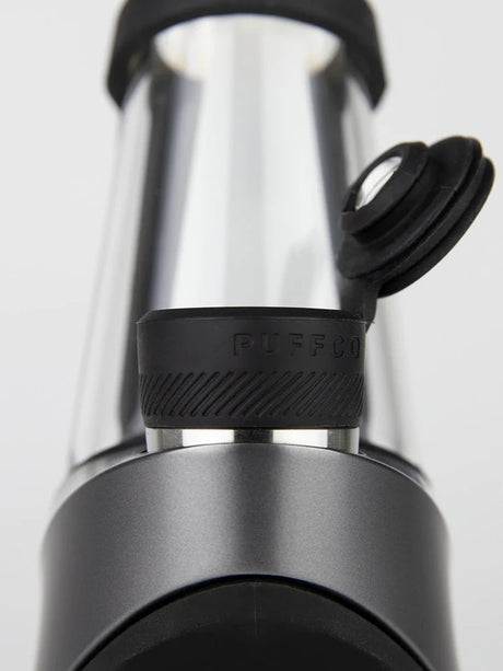 Macro view of Oculus-style cap and tether mounted to chamber, Puffco branding on textured silicone ring in Onyx.