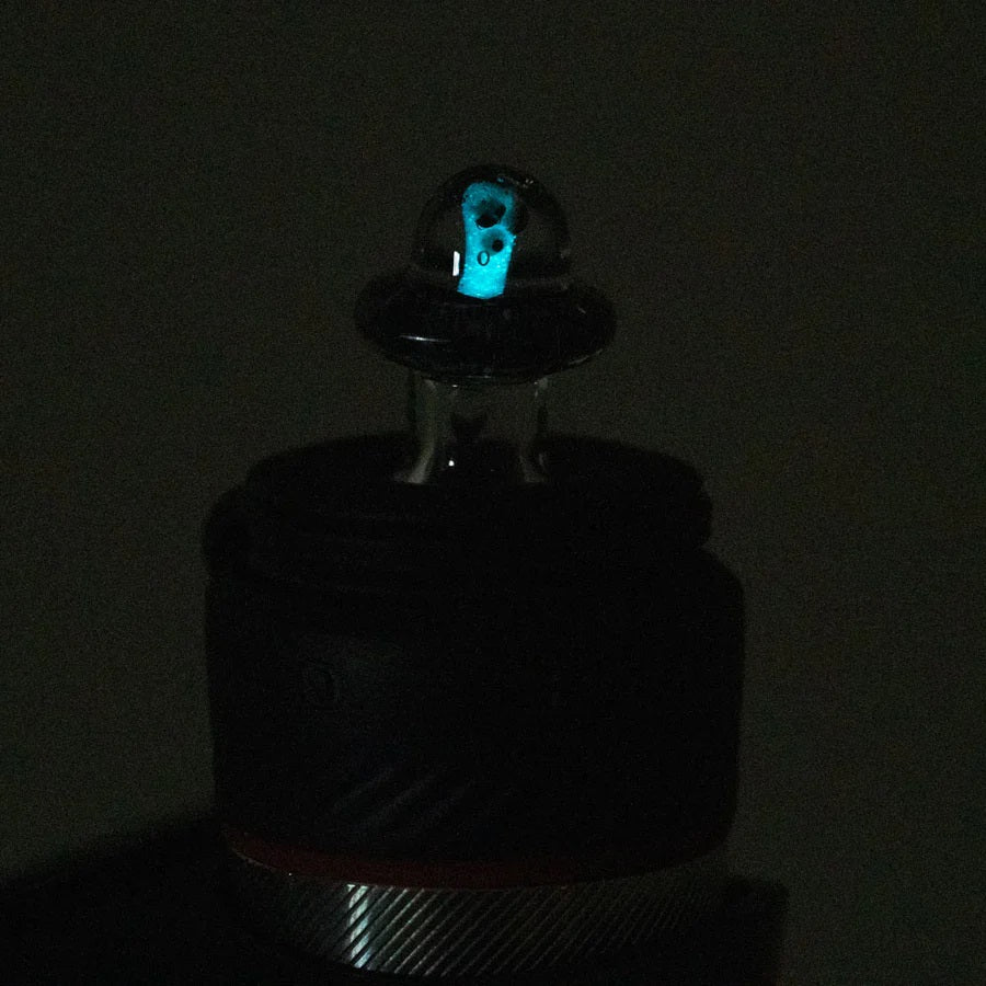 Low-light shot of the Martian cap on a Puffco Peak Pro showing a faint blue glow inside the clear dome.