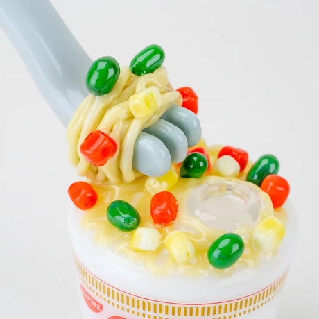 Closeup of fork wrapped in noodles with multicolor veggie accents surrounding a clear female joint on the cup lid.