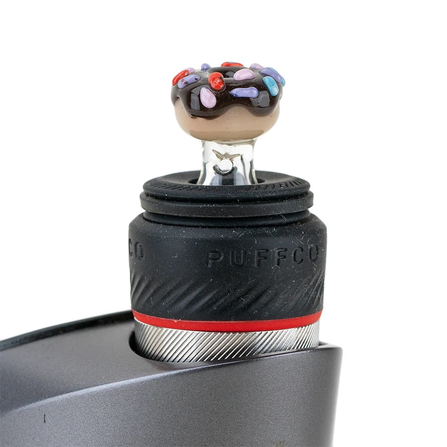 Donut Peak Pro ball cap installed on a Puffco device, showing chocolate icing, colorful sprinkles, and compact clear base for a snug fit.