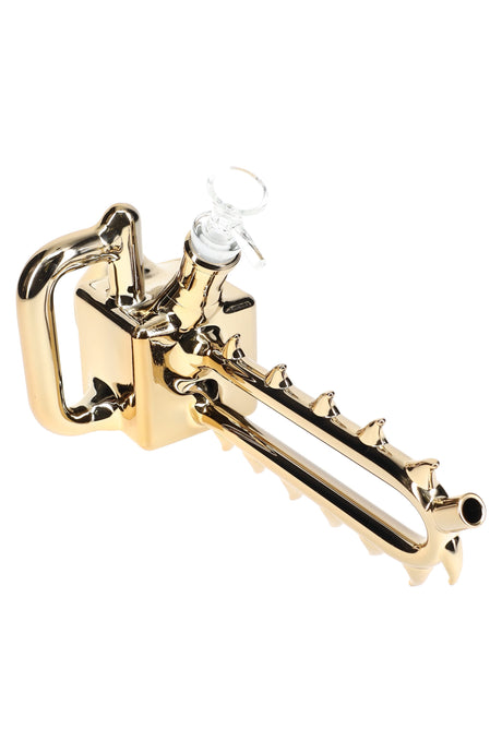Gold-finish chainsaw bong with integrated handle and spiked bar mouthpiece, glass herb bowl included, roughly 11″.
