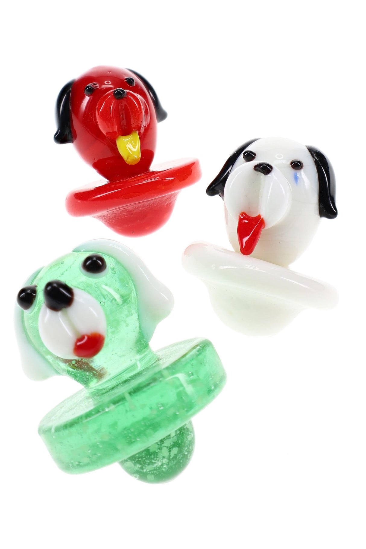 Trio of glass dog carb caps in red, white, and green with tongue-out faces and bubble bases for directional airflow on flat-top bangers.