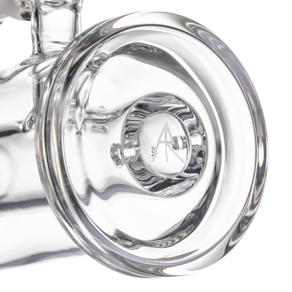Close-up of MJ Arsenal mini dab rig base with thick clear glass footing and etched logo detail