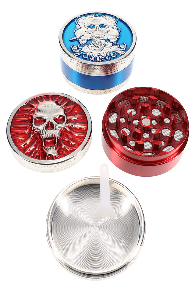 Colored 3-part metal herb grinder, 2″ size, skull-design lids in red and blue with mesh screen and kief scraper, pieces shown apart.