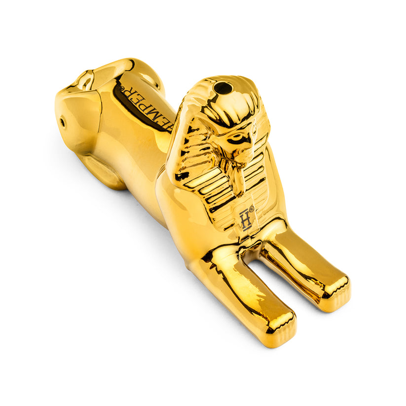 Angled overhead view of Hemper Sphinx gold glass hand pipe highlighting bowl on back, stretched paws, and shiny electroplated finish.
