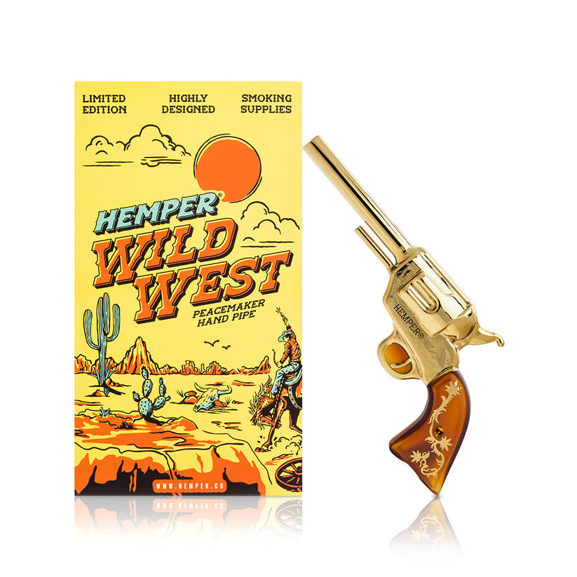 Hemper Peacemaker gold revolver glass hand pipe standing beside matching yellow Wild West box on bright white background.