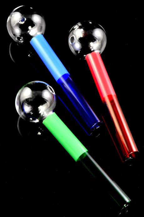 Three 6″ jumbo colored glass oil burners on black background, clear globe bowls with blue, red, and green stems; heavy feel.