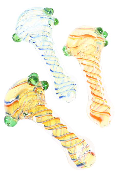 Color-changing Rasta striped glass spoon pipe with spiral bands and three green grip marbles, shown in assorted colorways.