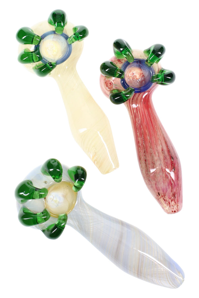 Silver-fumed color-changing glass spoon with green claw spikes around the bowl and tapered handle, shown in assorted colors.