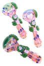 Color-changing pink glass spoon pipe with raised green leaves, flower marbles, dotted inlays, and side carb; glossy finish; sold individually.
