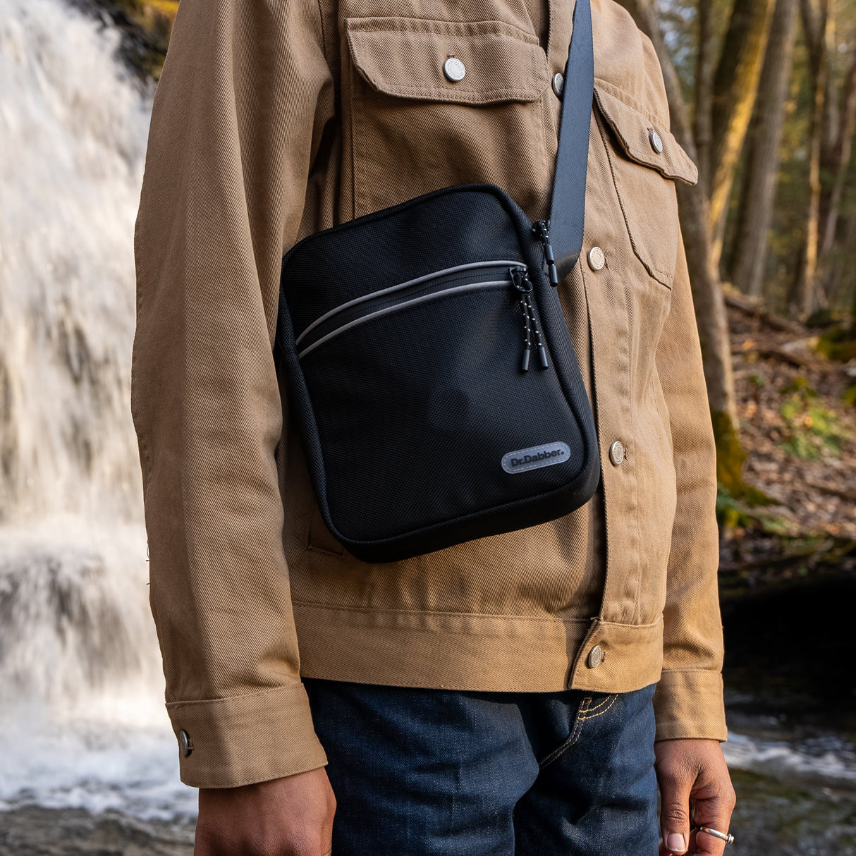 Black Dr. Dabber tour bag worn crossbody outdoors with textured shell and front accessory pocket