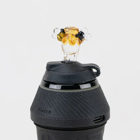 Close view of the bee-topped cap seated on a Puffco device, matching the Beehive Proxy Sherlock attachment styling.