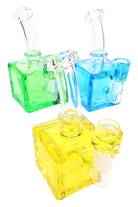Trio of small cube glass bongs in green, blue, and yellow with curved necks and fluid-filled chambers, stemless design.