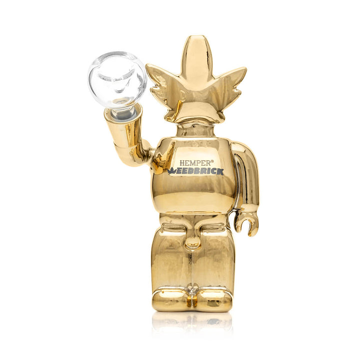 Angled view of mirror-gold Weedbrick glass bong with clear bowl and Hemper logo on base, compact daily-use setup