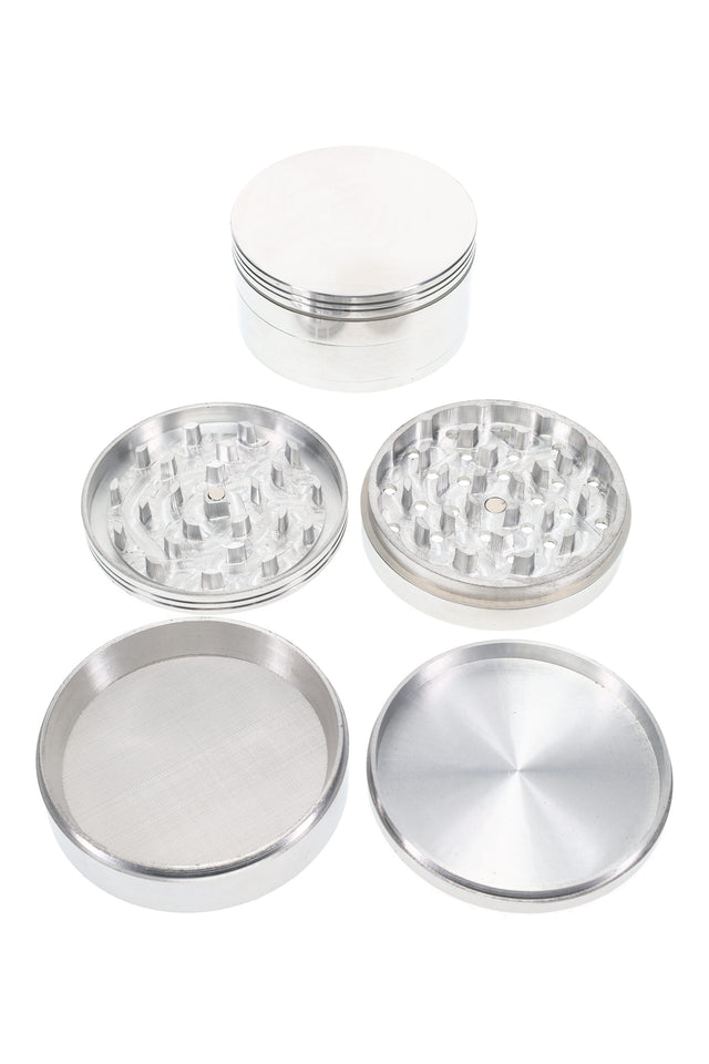 Large 4-part metal herb grinder with magnetic lid and textured grip, showing grind chamber, mesh screen, and kief catch.