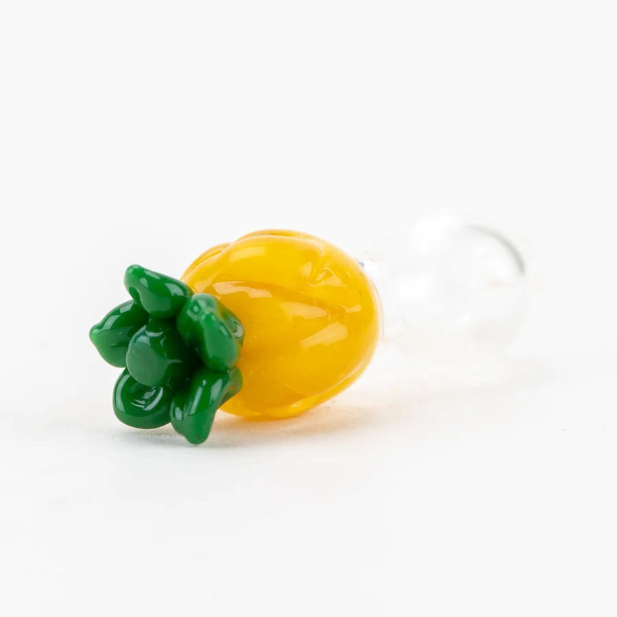 Close-up of the pineapple cap top showing raised green leaves and bright yellow texture with a clear glass base attached.