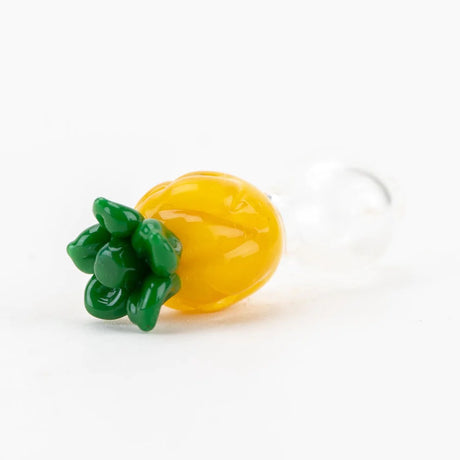 Close-up of the pineapple cap top showing raised green leaves and bright yellow texture with a clear glass base attached.