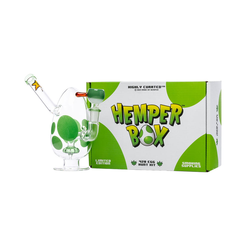 Green-spotted egg bong displayed with branded Hemper Box packaging on a studio-white backdrop.