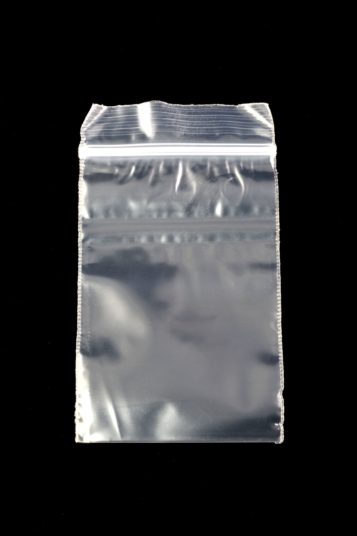 Single 2×3-inch Apple Bags clear mini zip baggie showing airtight zipper closure against a glossy black background