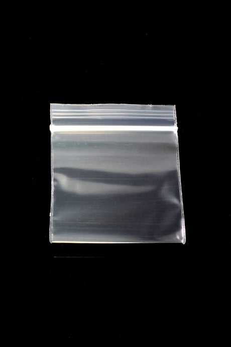 Single Apple Bags clear mini zip baggie, 1 ¾-inch square with re-sealable zipper, lying flat on glossy black background