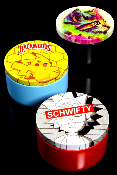 Three assorted-design metal stash jars arranged on glossy black surface, highlighting vibrant lid artwork and colorful bases