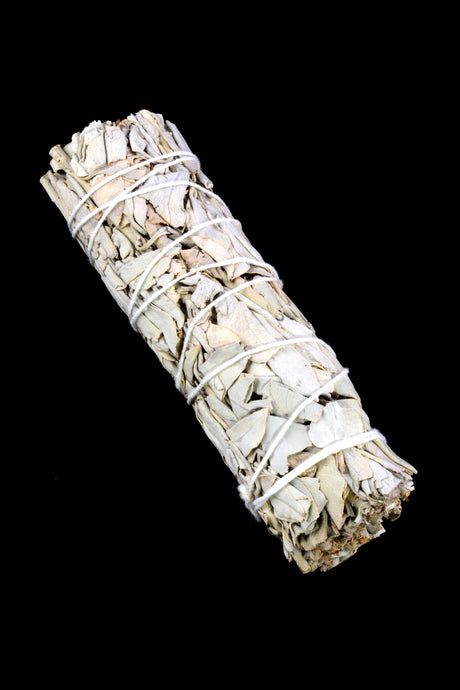 Six-inch California white sage smudge bundle bound in white string, shown diagonally on deep black background to accent leaf texture.