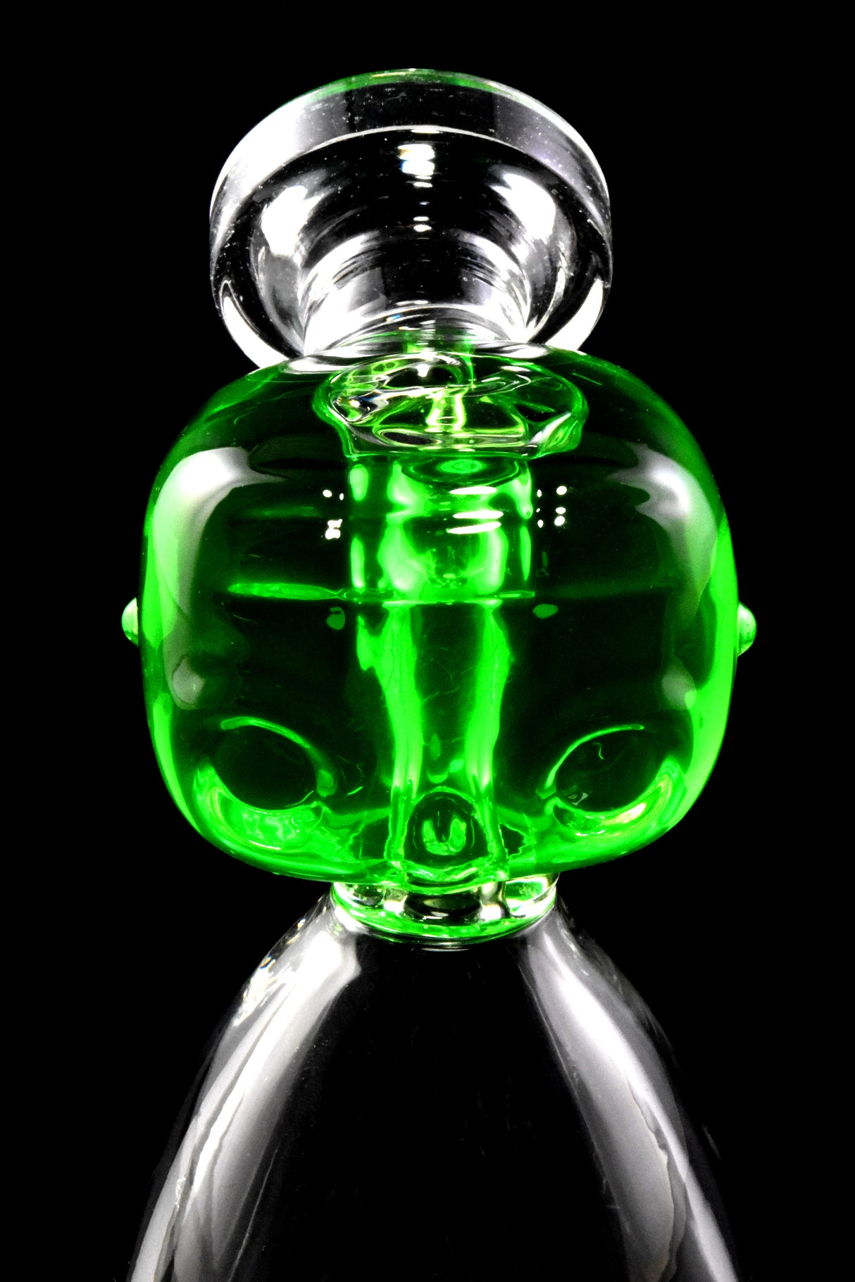 Close view of green fluid-filled alien head mouthpiece on a small clear beaker bong.