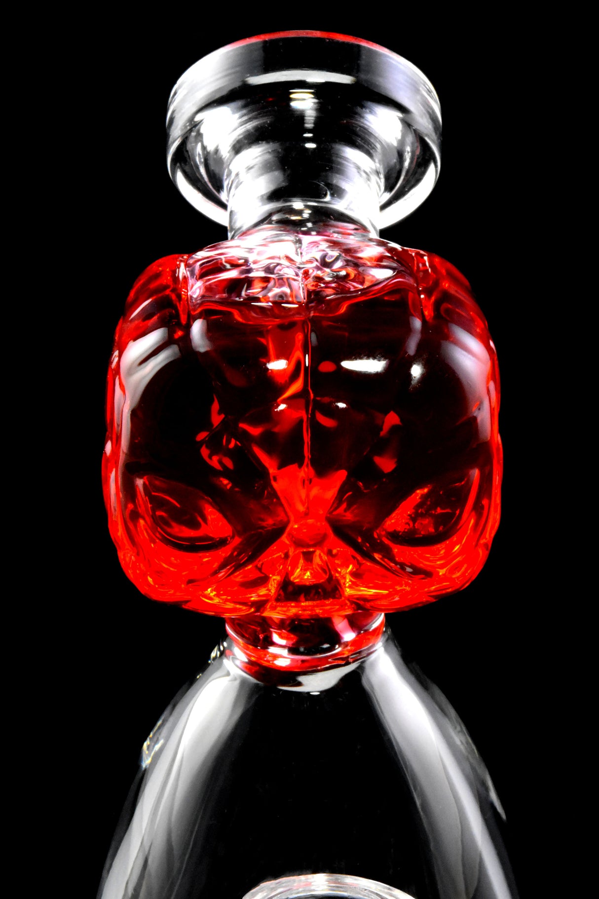 Close-up of red fluid-filled spider hero mouthpiece on a small glass beaker bong, sculpted face detail visible.