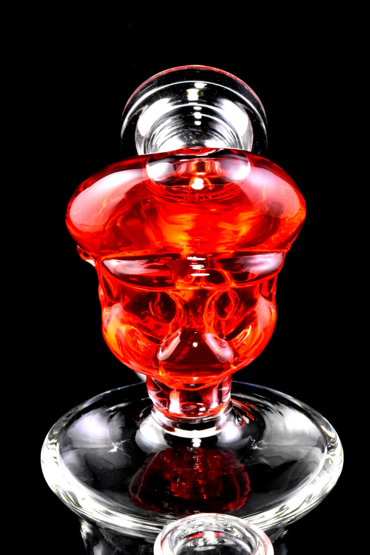 Close-up of red fluid-filled plumber character mouthpiece on a small glass bong, glossy details and rounded base shown.