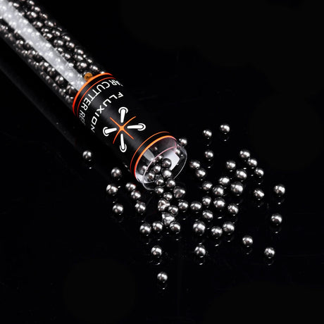 Flux Tar Cutter carbon bead refill tipped over on black surface with beads spilling in scattered pile