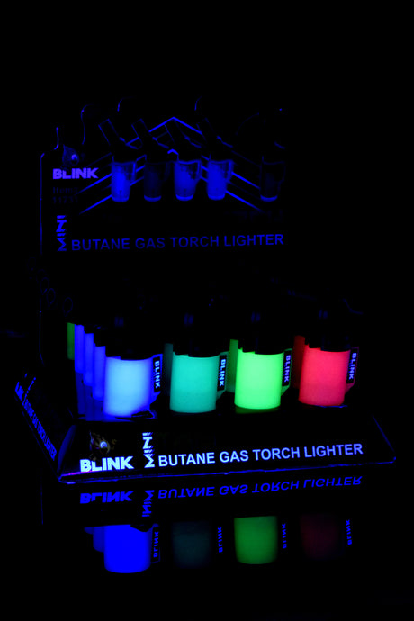 Dark-room shot of Blink Glow Mini Twisted 20-pack with tanks lit in blue, green, and red glow, countertop display view.