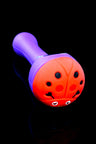 Purple silicone pipe with red ladybug cap design; clear bowl sits in the top opening.