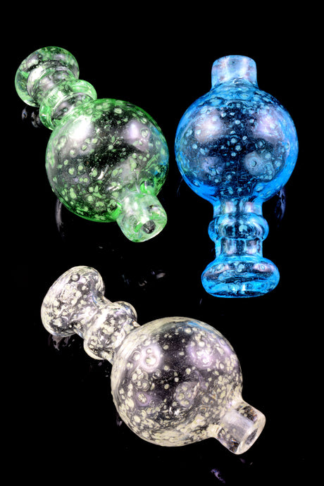 Trio of glow-in-the-dark frit glass bubble carb caps in green, blue, and clear on black background; short spout and round handle.