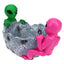 Pink and green alien duo gripping rugged silver crater-bowl resin ashtray, multiple cavity details and molded joint rests, studio white backdrop.