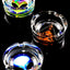 Trio of tempered glass ashtrays featuring alien and abstract artwork, side-by-side on reflective black surface.
