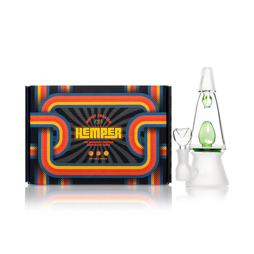 Front view of green Hemper That 70’s lava lamp bong next to colorful vintage-style Hemper box, display-ready setup on white.