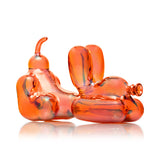 Side profile of 4″ Hemper Balloon Dog amber glass hand pipe focusing on balloon legs and raised belly bowl on white.