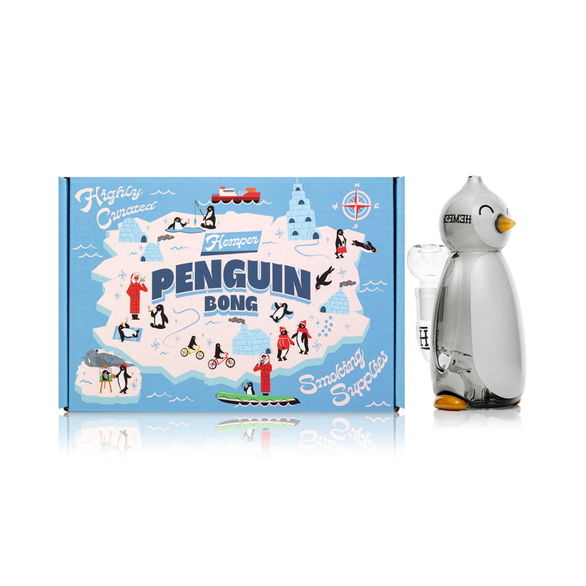 Front view of Hemper Penguin glass bong next to illustrated Arctic-themed gift box, ready-for-retail image highlighting the novelty glass bong shape.