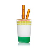 Rear angle of Hemper ramen cup bong showing white and green graphics, yellow lid and paired amber glass chopsticks.