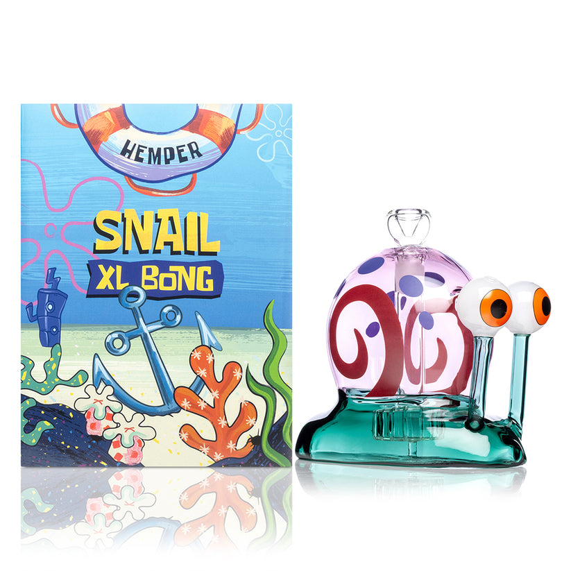 Side view of Hemper Snail XL 6 inch glass bong next to colorful ocean-themed retail box, showing full shell swirl graphic and wide stable base.
