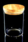 Large cylindrical glass storage jar featuring wide bamboo pop-top lid and silicone seal, close-up on black backdrop