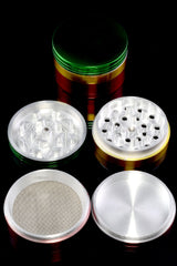 Tri-color rasta aluminum 4-piece weed grinder on black background; lid, teeth, fine mesh screen and base displayed.