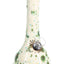 Off-white ceramic bong featuring teal and moss-green burst dots and gold accent, glass slide visible, studio lighting.